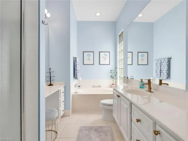 Bathroom with vanity, light tile patterned flooring, a bath, and recessed lighting