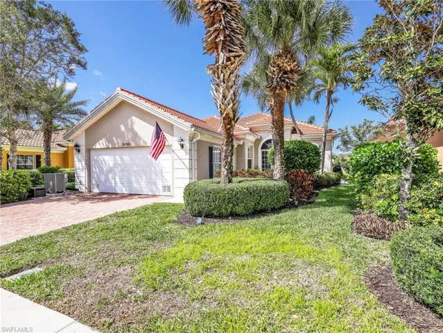 Mediterranean / spanish house with stucco siding, a garage, driveway, a front yard, and a tiled roof