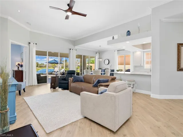Living room with a ceiling fan, light wood-type flooring, and ornamental molding