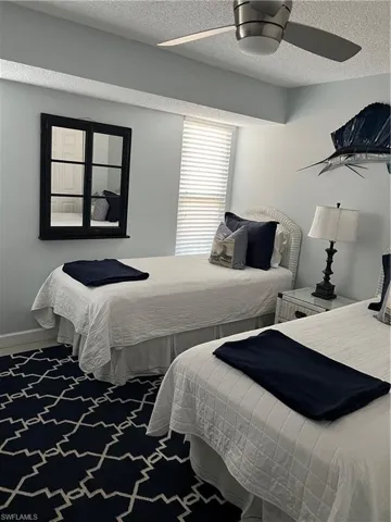 Bedroom with ceiling fan, a textured ceiling, and carpet floors