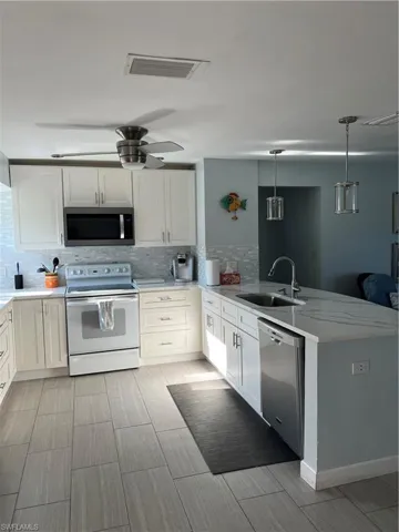 Kitchen with sink, dishwasher, stove, and tasteful backsplash