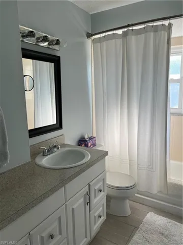 Full bathroom with shower / bath combo with shower curtain, a textured ceiling, vanity, and toilet