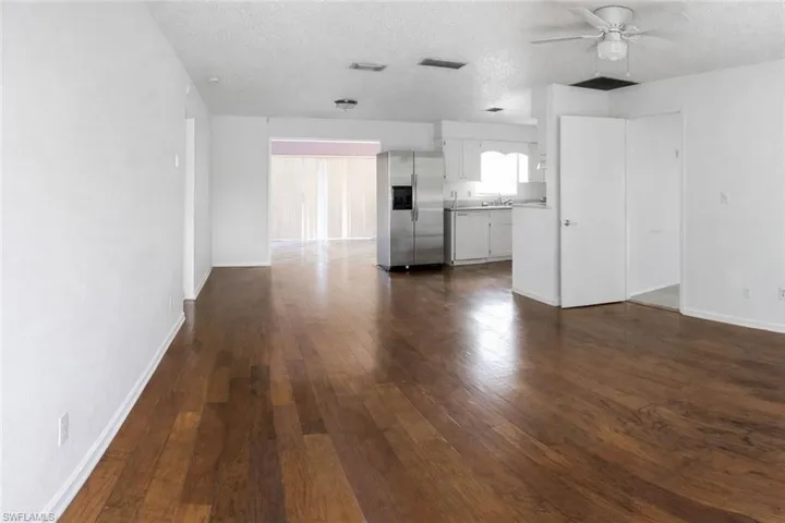 Unfurnished living room featuring ceiling fan, a textured ceiling, and dark wood-style floors