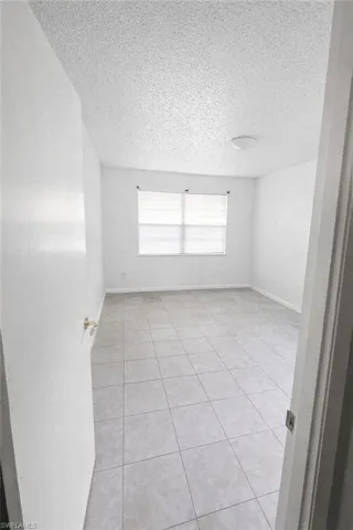 Empty room with light tile patterned floors and a textured ceiling