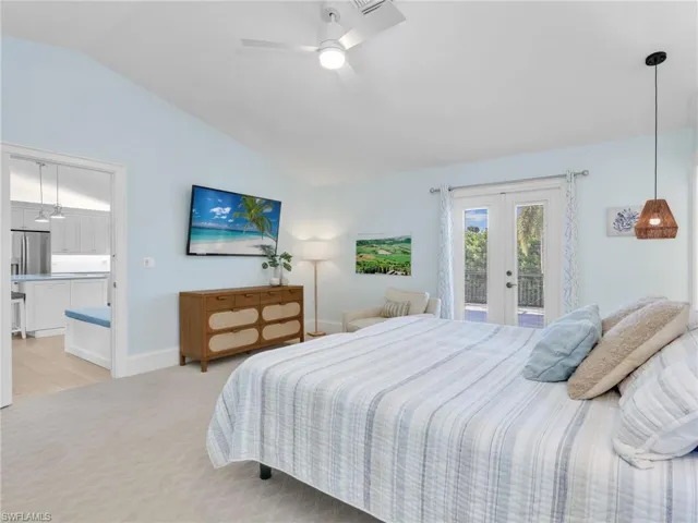Bedroom featuring french doors, vaulted ceiling, stainless steel fridge, light carpet, and access to exterior