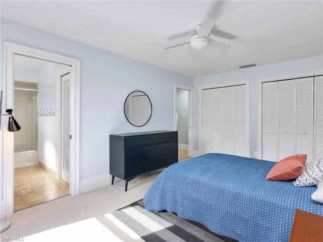 Bedroom with two closets, carpet floors, and ceiling fan