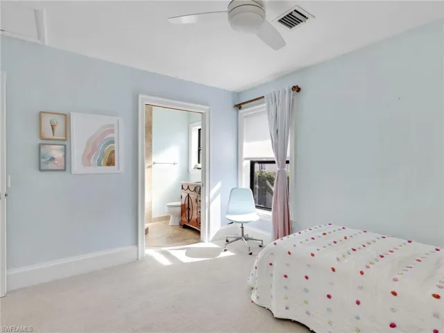 Carpeted bedroom featuring ensuite bath and ceiling fan