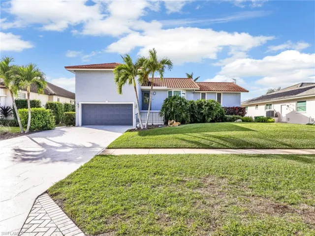View of front of house featuring concrete driveway, stucco siding, a front yard, a tiled roof, and a garage