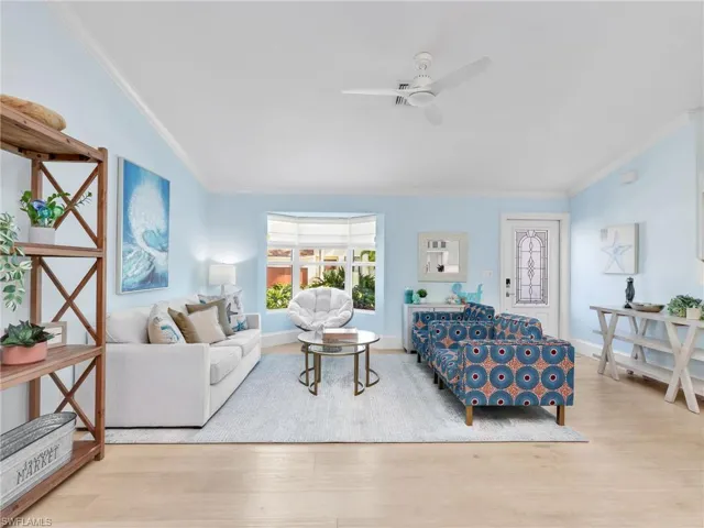 Living area featuring ornamental molding, light wood-style floors, and ceiling fan