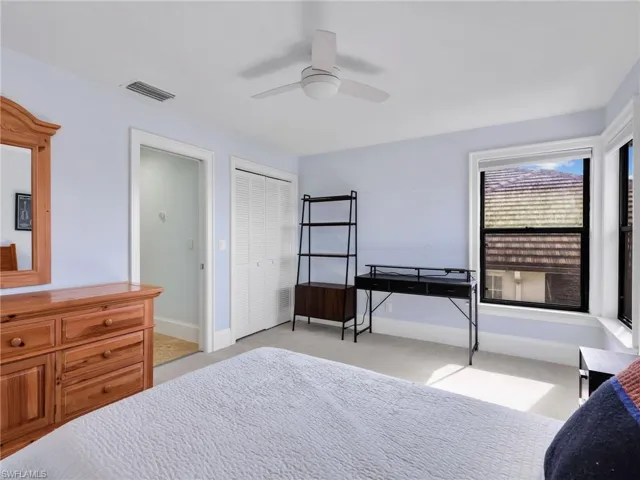 Bedroom with light colored carpet, a ceiling fan, and a closet