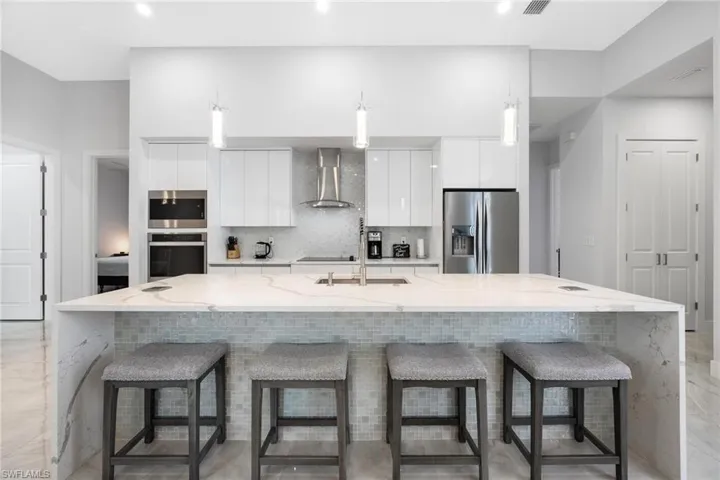 Kitchen featuring light stone countertops, modern cabinets, decorative backsplash, and a kitchen breakfast bar
