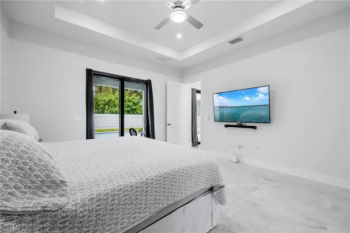 Bedroom with a tray ceiling, access to outside, ceiling fan, and recessed lighting