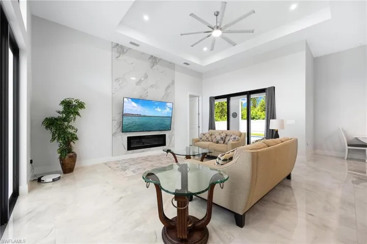 Living area featuring a fireplace, a raised ceiling, and ceiling fan