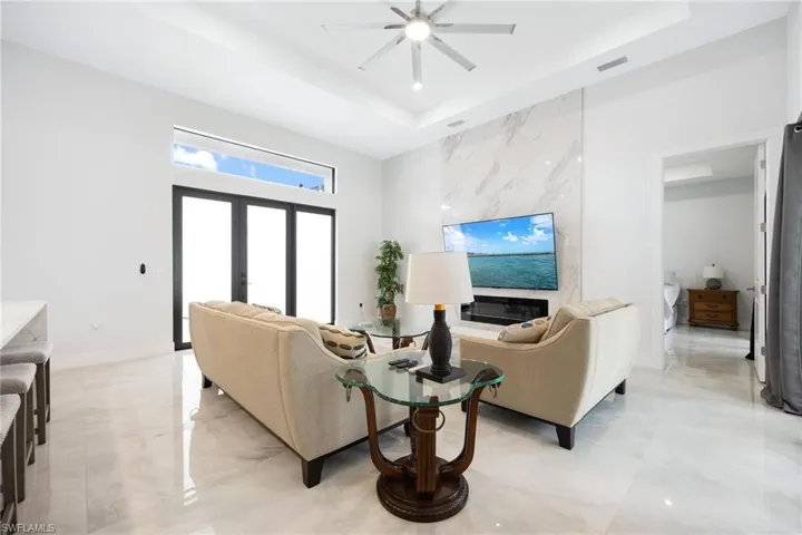 Living room featuring a raised ceiling, french doors, and ceiling fan