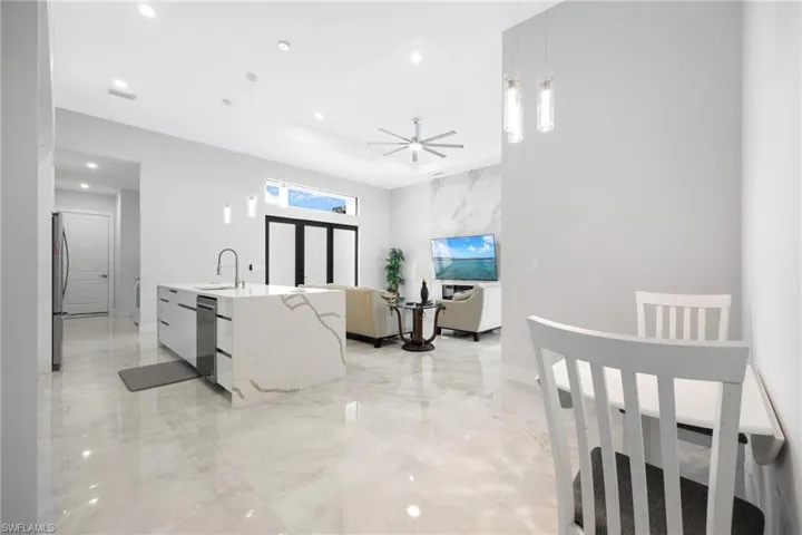 Kitchen with decorative light fixtures, light stone countertops, a ceiling fan, light marble finish floors, and recessed lighting