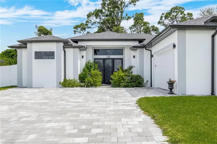 Prairie-style house with a garage, stucco siding, decorative driveway, and a front yard