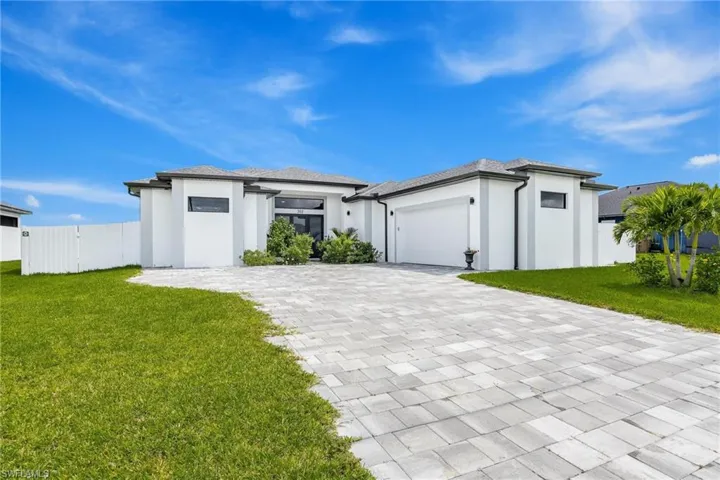Prairie-style house with an attached garage, decorative driveway, and stucco siding