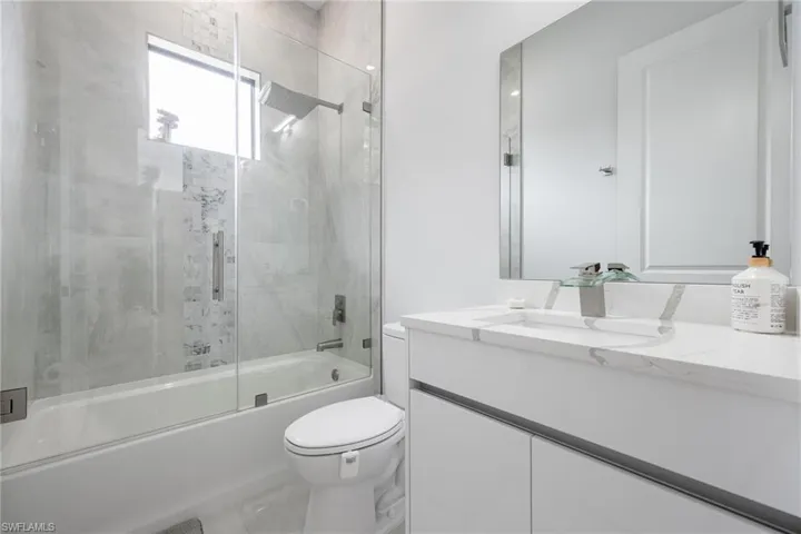 Full bath featuring shower / bath combination with glass door and vanity