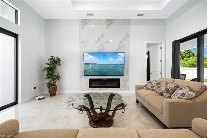 Living room with tiled floors, a high end fireplace, and a raised ceiling