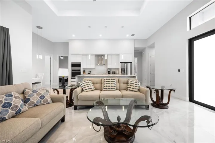 Living area with a tray ceiling, a high ceiling, and recessed lighting