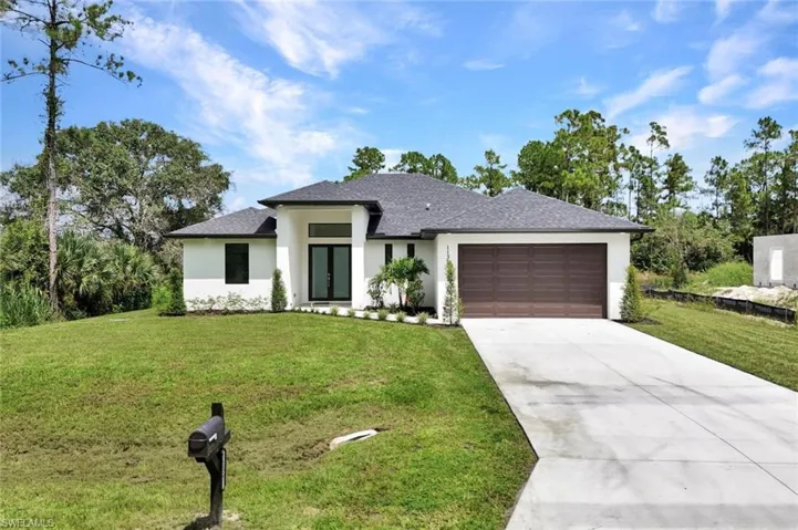 Prairie-style home featuring stucco siding, a front yard, and concrete driveway