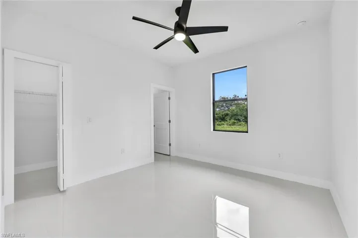 Unfurnished bedroom with a walk in closet and a ceiling fan