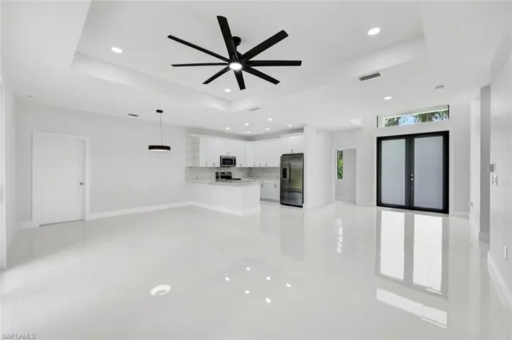 Unfurnished living room with french doors, a raised ceiling, recessed lighting, and ceiling fan