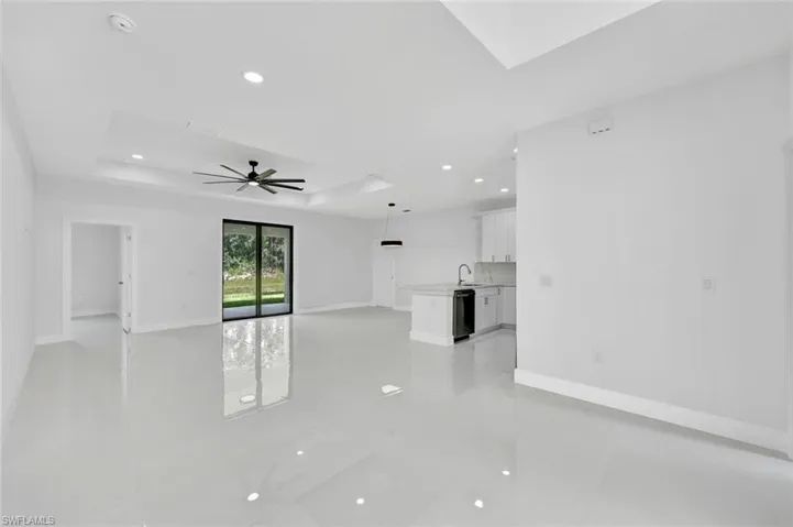 Unfurnished living room featuring ceiling fan, a raised ceiling, and recessed lighting