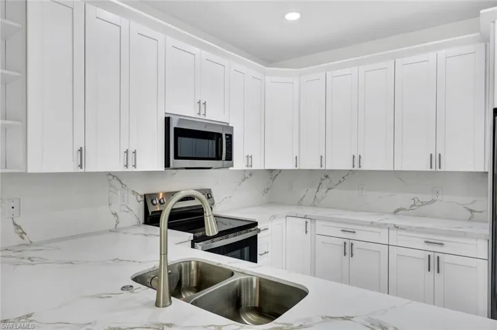 Kitchen featuring stainless steel appliances, white cabinetry, light stone countertops, open shelves, and recessed lighting