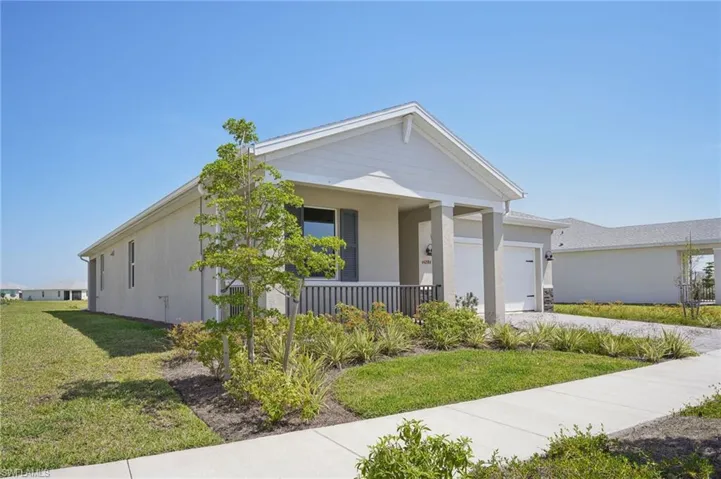 View of front of house with an attached garage, a front lawn, concrete driveway, and covered porch