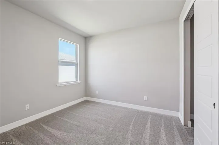 Unfurnished bedroom with carpet flooring and baseboards