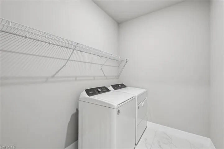 Laundry room featuring washer and dryer, baseboards, and marble finish floors