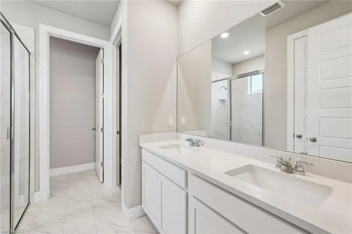 Bathroom with marble finish flooring, a marble finish shower, baseboards, double vanity, and recessed lighting