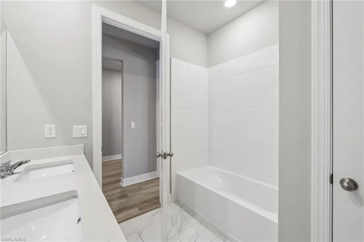 Full bathroom with baseboards, bathing tub / shower combination, double vanity, and recessed lighting
