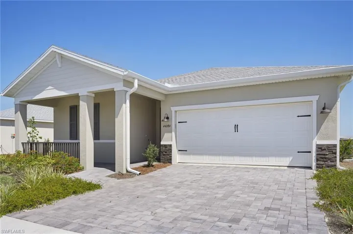 Ranch-style home featuring decorative driveway, stucco siding, a garage, and stone siding