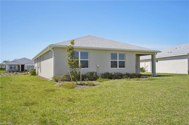 Back of house featuring a lawn and stucco siding
