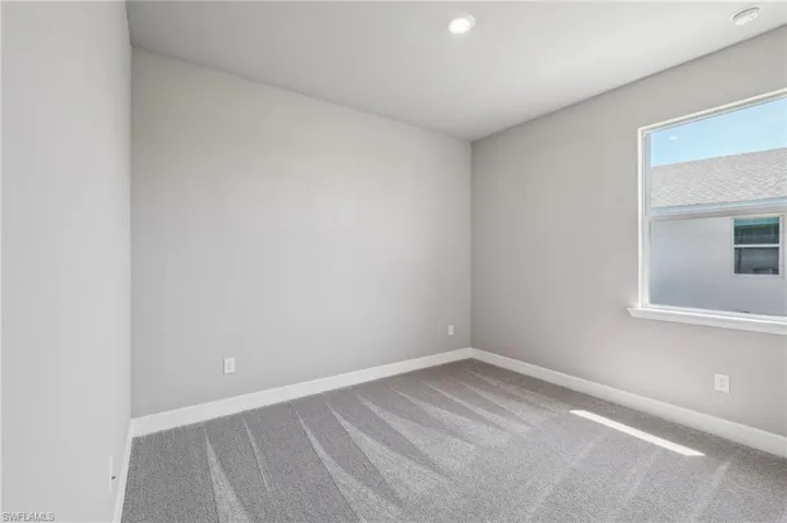 Carpeted spare room with baseboards and recessed lighting