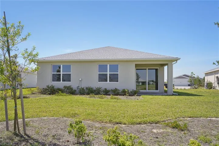 Rear view of property with stucco siding and a lawn