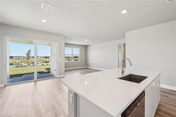 Kitchen with a sink, dishwasher, baseboards, light wood-style floors, and recessed lighting