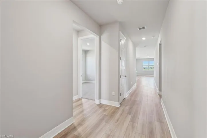 Hallway with light wood-type flooring, baseboards, and recessed lighting