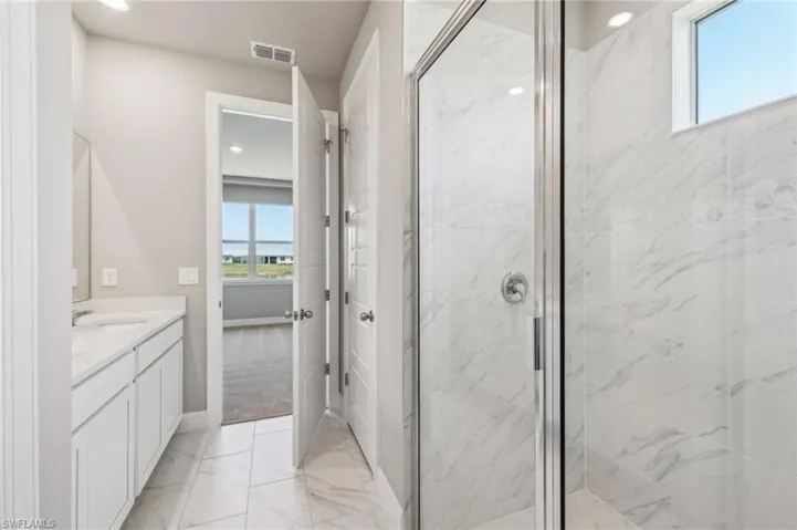 Full bathroom with a marble finish shower, vanity, baseboards, marble finish flooring, and recessed lighting