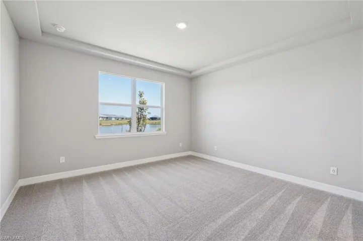 Carpeted spare room featuring baseboards, a smoke detector, recessed lighting, and a water view