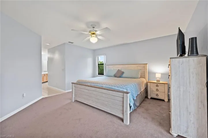 Bedroom featuring light carpet, a ceiling fan, and connected bathroom