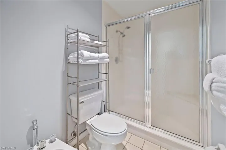 Bathroom with a stall shower, tile patterned floors, and a bidet