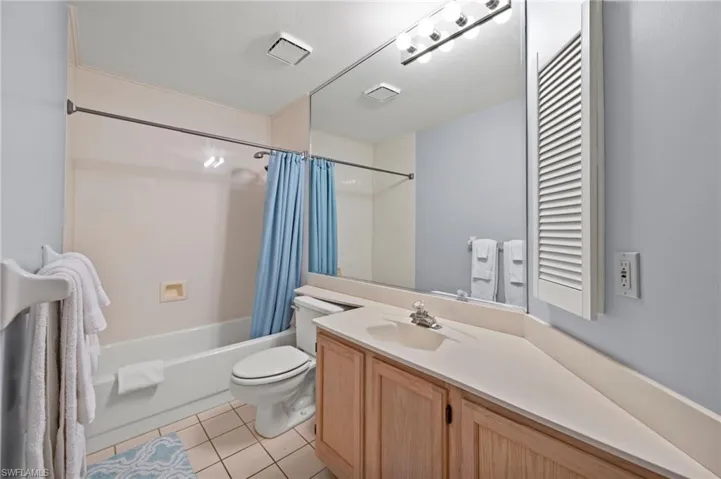 Bathroom featuring vanity, shower / tub combo, and tile patterned flooring