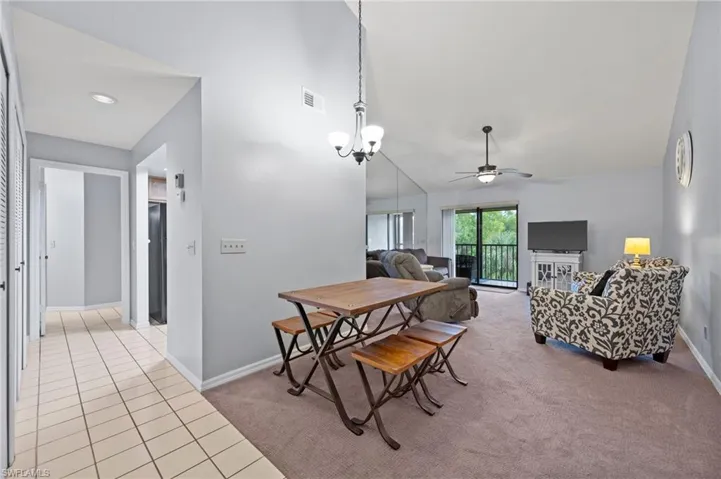 Dining room with a ceiling fan, light carpet, light tile patterned floors, and high vaulted ceiling