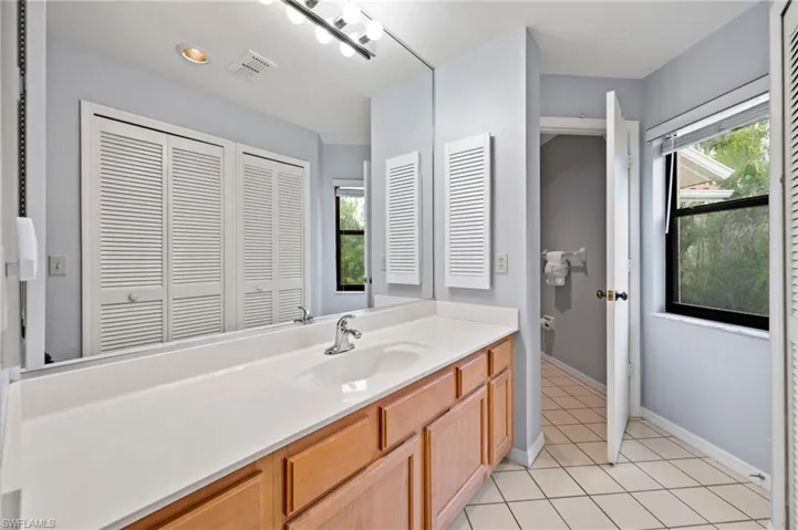 Bathroom with vanity, a closet, and tile patterned floors