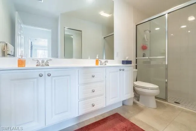 Bathroom with tile patterned flooring, vanity, toilet, and a shower with shower door