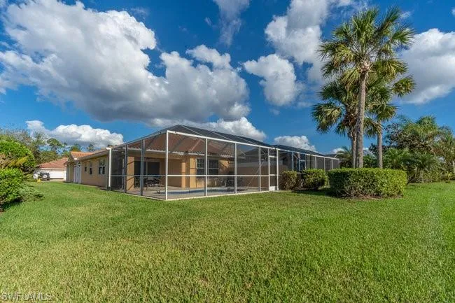 Back of house with a lanai and a lawn