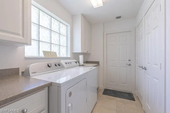 Washroom featuring cabinets, light tile patterned floors, and independent washer and dryer